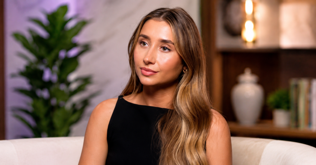 Lily Phillips during a studio interview, wearing a black sleeveless top with a calm expression against a modern indoor background.
