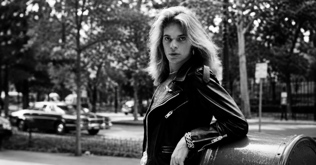 Black-and-white portrait of David Lee Roth wearing a black leather jacket and looking toward the camera.